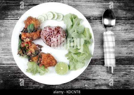 Organische rot braun Jasmin Reis mit würzigen sauer Fried Chicken Salat Anruf Khao yum Kai zap in Thai. Stockfoto