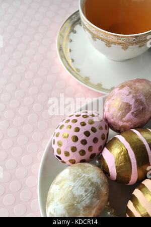 Dekoriert gold Ostereier mit Punkten und Streifen auf blush Pfirsich rosa Hintergrund. Styled lieferbar Bild mit kopieren. Ostern und Frühjahr Thema. Stockfoto