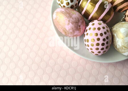 Dekoriert gold Ostereier mit Punkten und Streifen auf blush Pfirsich rosa Hintergrund. Styled lieferbar Bild mit kopieren. Ostern und Frühjahr Thema. Stockfoto