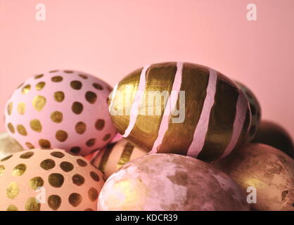 Dekoriert gold Ostereier mit Punkten und Streifen auf blush Pfirsich rosa Hintergrund. Styled lieferbar Bild mit kopieren. Ostern und Frühjahr Thema. Stockfoto