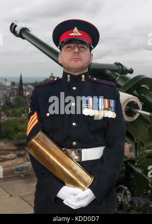 Bezirk Gunner Sergeant Dave Beveridge posiert mit leeren Schale nach dem Feuern die One o'clock Gun im Edinburgh Castle in Schottland. Stockfoto