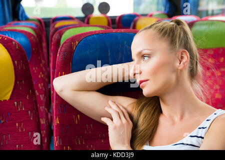 Eine junge Frau sitzt bequem auf dem Bus. Stockfoto