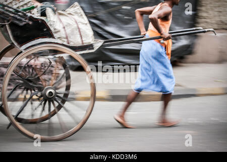 Indische Mann in der Bewegung Ziehen einer Hand gezeichnet Rikscha auf Kolkata Straßen in Indien. eine der letzten Bastionen der alten Verkehrsträger Stockfoto