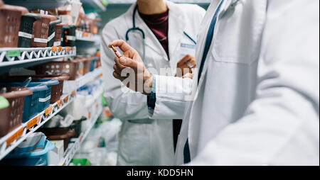 Zwei Apotheker auf der Suche nach kritischen Arzneimittel. Männlicher Arzt ein Medikament mit weiblichen stehen in der Pharmazie. Stockfoto