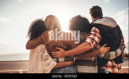 Gruppe junger Freunde, die zusammen stehen und Blick auf das Meer. Ansicht der Rückseite vier junge Leute bewundern Sie die Aussicht. Stockfoto