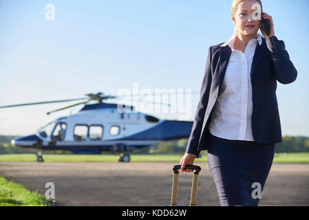 Geschäftsfrau zu Fuß entfernt von Hubschrauber während Gespräch am Handy Stockfoto