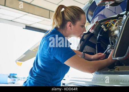 Weibliche Aero Engineer, der an Helikopter im Hangar Stockfoto