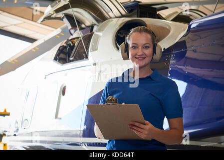 Portrait von weiblichen aero Ingenieur mit Zwischenablage Durchführung prüfen auf Helikopter im Hangar Stockfoto