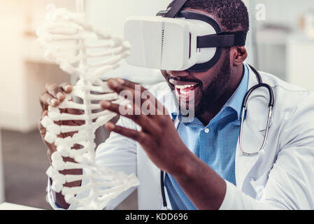 Begeisterte junge Praktikerin in Virtual-Reality-Brille, die DNA-Modell berührt Stockfoto