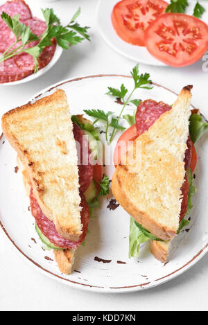 Hausgemachte Club Sandwiches mit Salami, Tomaten, Gurken und Kopfsalat. Stockfoto