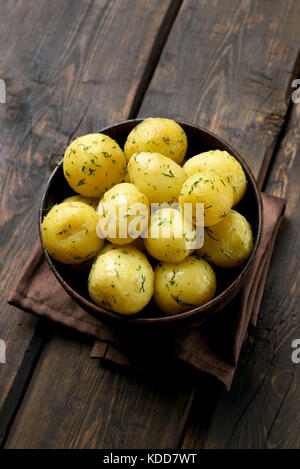 Gekochte Kartoffeln mit Dill in der Schüssel auf hölzernen Hintergrund Stockfoto