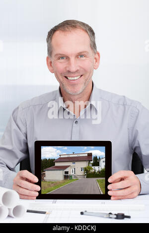 Gerne reife Architekt zeigt Bild von Haus auf digital Tablet Stockfoto