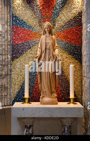 Holz geschnitzte Statue der Maria Mutter Gottes mit 12 Sterne Krone stehend auf Mond und Schlange an der Seite Altar mit Kerzen in einer Römisch-katholischen Kirche Stockfoto