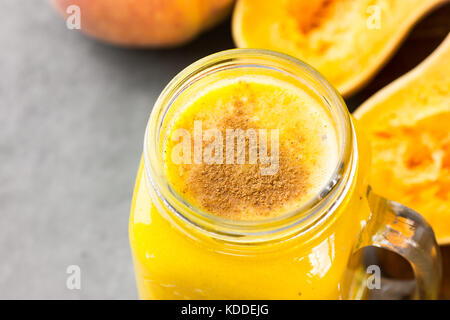Glas Marmeladenglas mit rohen Kürbis Kürbis Smoothie mit Pfirsiche, Bananen, Gewürze. Zutaten auf dunklen steinernen Tisch. BIGHT Farben, Ansicht von oben. Stockfoto