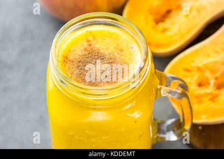 Glas Marmeladenglas mit rohen Kürbis Kürbis Smoothie mit Pfirsiche, Bananen, Zimt, Gewürze. Zutaten auf dunklen steinernen Tisch. BIGHT Farben, Clo Stockfoto