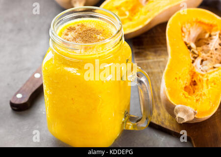 Raw vegan Kürbis Kürbis Smoothie mit Bananen, Pfirsiche, Zimt, pie Gewürze. Holz Schneidebrett, Zutaten auf dunklen konkreten Hintergrund. Stockfoto