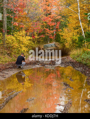Ein Jeep Wrangler rubicon Laden durch Wasser und Schlamm Loch in der Adirondack Wildnis im Herbst, mit einem Fotografen, Handy Bilder. Stockfoto