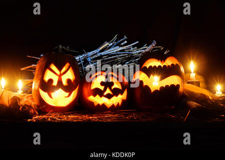 Foto für den Urlaub Halloween. Drei böse Kürbisse und ein Korb mit verschiedenen Gemüsen und Kerzen Stockfoto