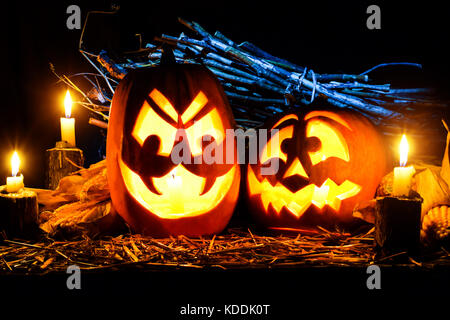 Foto für den Urlaub Halloween. Zwei böse Kürbisse von Kerzen und Mais auf einem dunklen Hintergrund umgeben. Bild für Postkarte mit Kopie Raum Stockfoto
