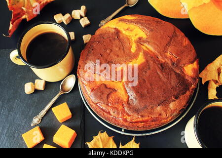 Kürbis Schokoladenkuchen auf dunklem Hintergrund mit Herbstlaub, Ansicht von oben Stockfoto