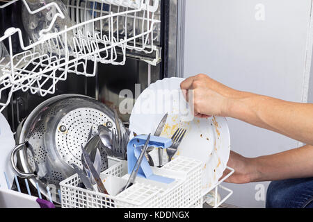 Hausfrau setzt dreckiges Geschirr in der Spülmaschine. Horizontal. Stockfoto