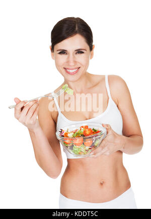 Schöne junge Frau genießen essen Salat auf weißem Hintergrund Stockfoto