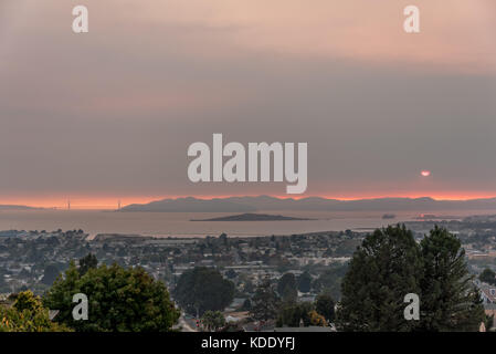 San Francisco, USA. 12 Okt, 2017. Blick nach Westen über die Bucht von San Francisco von der East Bay Hügel mit Golden Gate Brücke nach links, wie die Sonne durch wildfire Rauch über die Marin Headlands, südlich des Sonoma und Napa Waldbrände. Luftqualität an diesem Tag war so schlecht in San Francisco, in Peking, China bewertet. 12. Oktober, 2017. Credit: Shelly Rivoli/Alamy leben Nachrichten Stockfoto