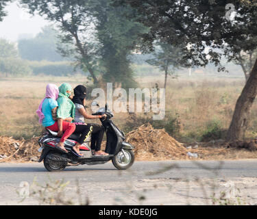 Shankar, panjab, Indien. 13. Oktober 2017. das Leben auf der Straße in Shankar, ländlichen indischen Dorf. Menschen in der morgendlichen Fahrt zur Schule und Arbeit. den Landwirten vor Ort ihre Ware durch Traktor. wenige Leute tragen Schutzhelme, so gibt es eine hohe Rate von Verletzungen und Unfällen Kredit: wansfordphoto/alamy leben Nachrichten Stockfoto