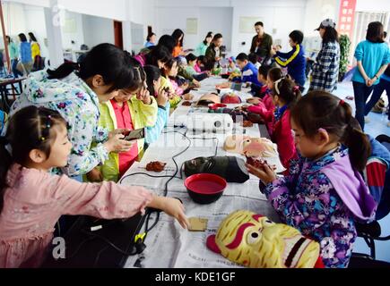 Enshi, China. Oktober 2017. Studenten lernen Masken der Nuo Opera in der Autonomen Präfektur Enshi Tujia und Miao in der zentralchinesischen Provinz Hubei zu machen. Masken sind ein charakteristisches Merkmal der Nuo-Oper, einem antiken Volksdrama, das in vielen chinesischen Provinzen entlang des Yangtse-Flusses immer noch beliebt ist. Es wird angenommen, dass die Darsteller der Nuo Opera die Fähigkeit erlangen, mit den Göttern zu kommunizieren, sobald sie ihre Masken tragen. Quelle: ZUMA Press, Inc./Alamy Live News Stockfoto