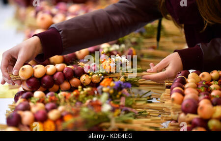 Weimar, Deutschland. Oktober 2017. Auf dem 364. Weimarer Zwiebelmarkt in Weimar am 13. Oktober 2017 werden die traditionellen Zwiebelstränge auf einem Marktstand verkauft. Das berühmteste Volksfest Thüringens zieht bis zum 15. Oktober rund 300,000 Besucher an. Rund 500 Stände bieten die beliebten rot-weiß geflochtenen Zwiebelbündel, warme Zwiebeltorte, Thüringer Bratwurst, Getränke und Kunsthandwerk an. Quelle: Martin Schutt/dpa-Zentralbild/dpa/Alamy Live News Stockfoto