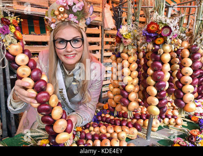 Weimar, Deutschland. 13. Oktober 2017. Die Zwiebelmarktkönigin, die 19-jährige Gina-Marie Hildebrandt-Kanhold, präsentiert auf dem Weimarer Zwiebelmarkt 364. die traditionellen geflochtenen Zwiebelbrötchen. Weimarer Zwiebelmarkt) in Weimar, Deutschland, 13. Oktober 2017. Bis zum 15. Oktober lockt Thüringens berühmtestes Volksfest rund 300,000 Besucher an. Rund 500 Stände bieten die beliebten rot-weißen zwiebelgeflochtenen Bunchs, warme Zwiebeltarte, Thüringer Bratwurst, Getränke und Kunsthandwerk. Quelle: Martin Schutt/dpa-Zentralbild/dpa/Alamy Live News Stockfoto