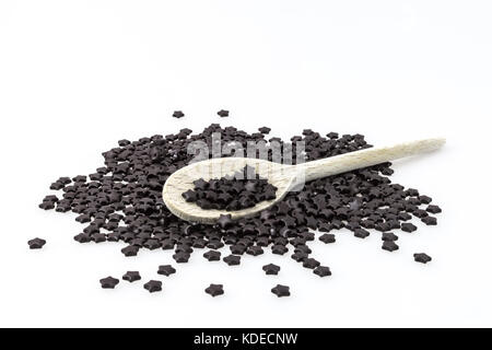 Süßholz-Form schwarz auf weißem Hintergrund zum Stern in der Mitte, in einem Löffel aus Holz. Stockfoto