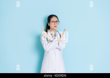 Ruhe Professional Female Klinik Arzt Hände palm Kreuz zu verweigern Geste zur Verhinderung medizinischer Ressourcen isoliert auf blauen Wand backgr Missbrauch Stockfoto