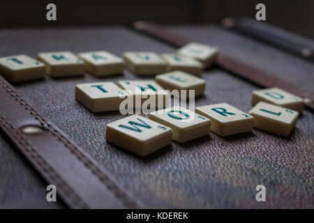 Reisen die Welt scrabble tiles Leder Koffer Hintergrund Stockfoto