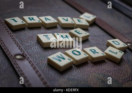 Reisen die Welt scrabble tiles Leder Koffer Hintergrund Stockfoto