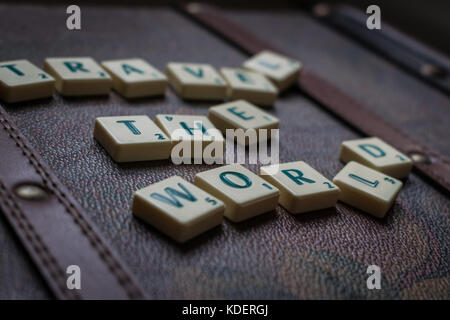 Reisen die Welt scrabble tiles Leder Koffer Hintergrund Stockfoto