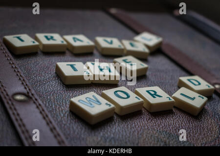 Reisen die Welt scrabble tiles Leder Koffer Hintergrund Stockfoto