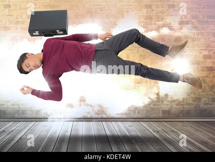 Digital composite der Geschäftsmann mit Aktenkoffer floating magisch über bewölkt Wand mit beleuchteter Bursts Stockfoto