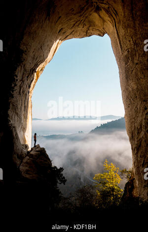 Aitzulo Höhle mit Silhouette einer Person, Meer aus Wolken und Bergen – Herbstmorgen im Baskenland Stockfoto