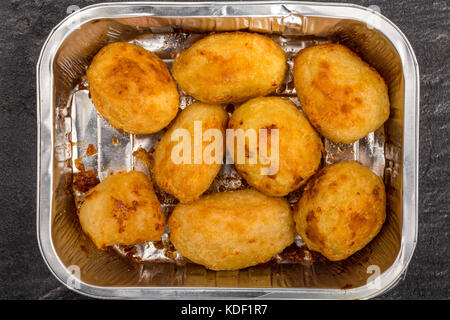 Bratkartoffeln in einem silbernen Backofen Backblech auf schwarzem Schiefer Küche Fliesen Stockfoto