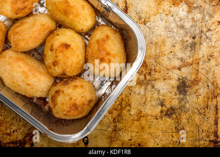 Bratkartoffeln in einem silbernen Backofen Backblech auf einem distressed Backblech mit Kopie Raum Stockfoto