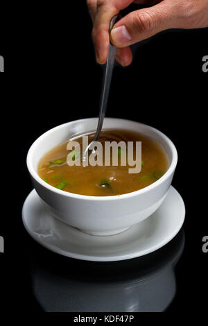 Heiße Tasse Miso Suppe mit Frühlingszwiebeln und Seetang mit einem Löffel gespeichert werden. Stockfoto