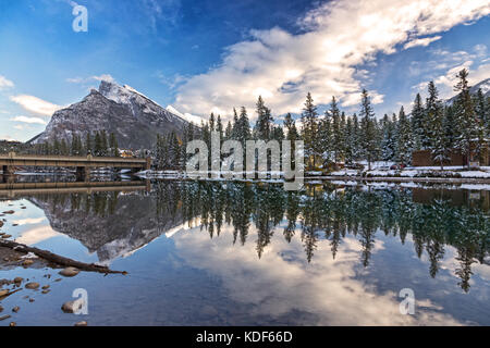 Die Bow River Bridge und die verschneite Mount Rundle spiegeln sich in einer ruhigen, landschaftlich schönen Wasserlandschaft wider. Banff National Park Rocky Mountains Alberta Kanada Stockfoto