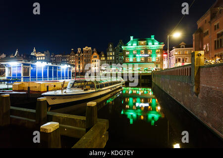 Amsterdam, Niederlande, 01. Juli 2016: Touristische boote in der Bucht vor dem Hintergrund der Traditionellen holländischen Häuser in Abend Stockfoto