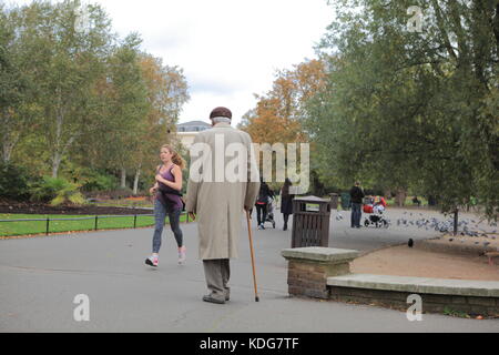 Alte asiatische Mann mit weißem Haar wandern im Regents Park, London, mit einem Stock Stockfoto