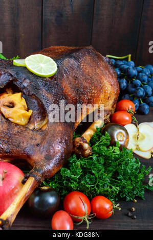 Gans im Ofen gebacken mit Äpfeln und Trauben. Weihnachten Gans auf einer hölzernen Hintergrund. Festliche Schale. Stockfoto