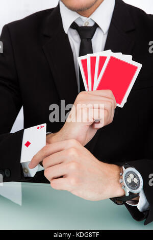 Portrait einer jungen Geschäftsmann mit Spielkarten in der Hülse Stockfoto