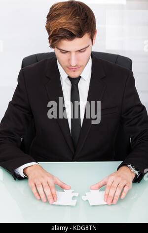 Portrait einer jungen Geschäftsmann Lösung Puzzle im Büro Stockfoto