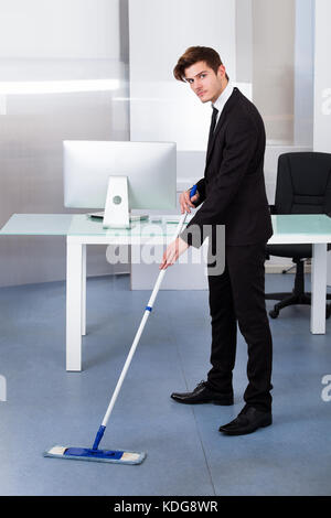 Portrait einer jungen Geschäftsmann Reinigung Büro mit Mop Stockfoto