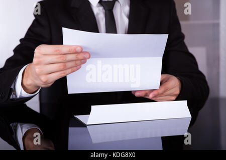 Nahaufnahme des Kaufmanns holding Dokument am Schreibtisch Stockfoto